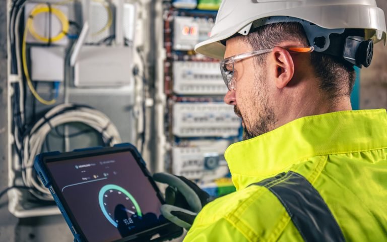 Man, an electrical technician working in a switchboard with fuses. Installation and connection of electrical equipment.